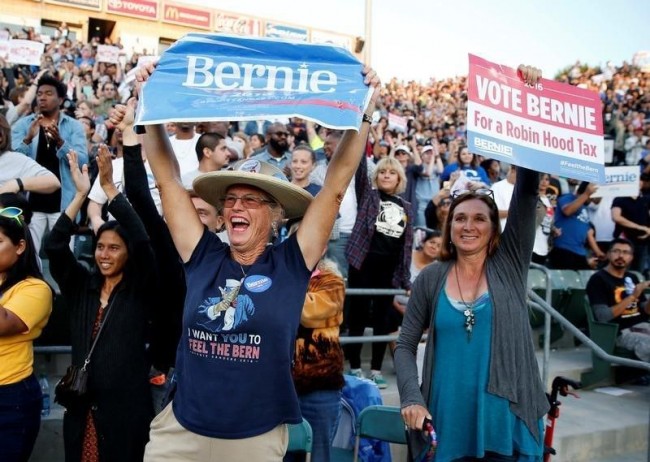 Women hold up signs and cheer as they wait for U.S. Democratic presidential candidate Bernie Sanders to speak during a rally in Carson, California, U.S., May 17, 2016. REUTERS/Mike Blake