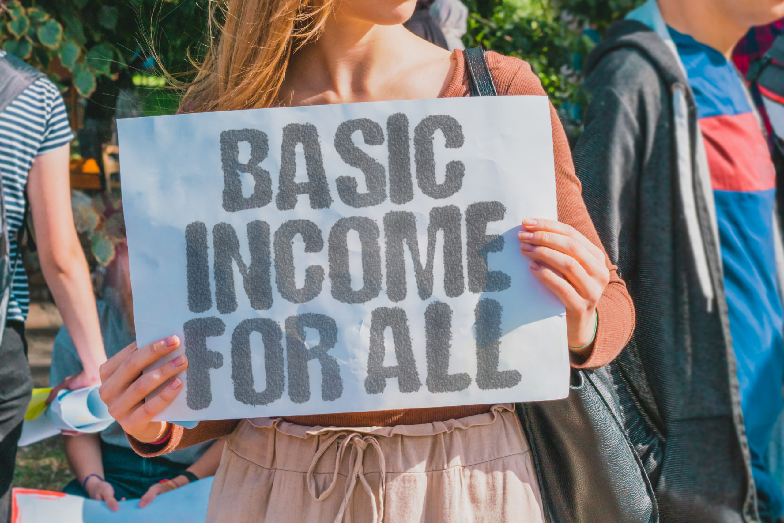 woman holding sign, basic income for all